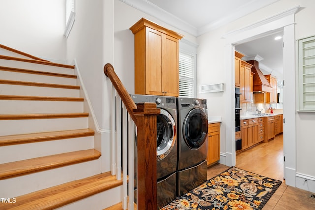 clothes washing area with crown molding, washer and dryer, a sink, cabinet space, and light tile patterned floors