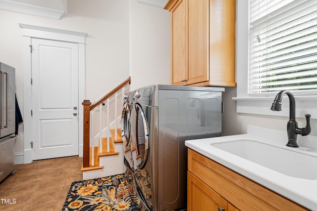 laundry area featuring washing machine and clothes dryer, a sink, and cabinet space