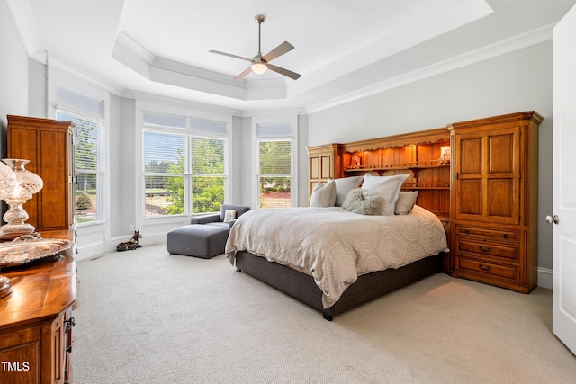 bedroom with light colored carpet, ornamental molding, a ceiling fan, and a tray ceiling