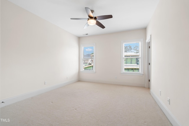 empty room with baseboards, visible vents, a ceiling fan, and light colored carpet