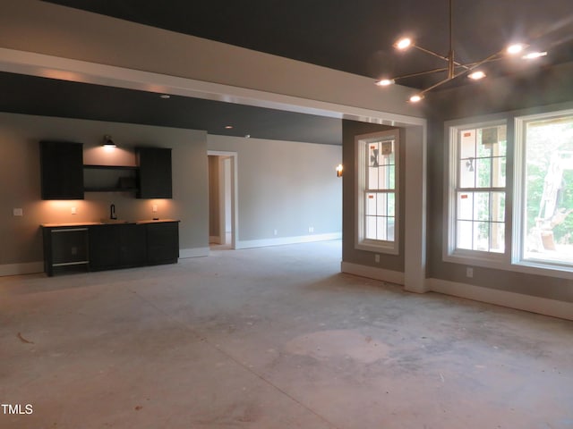 2590 Silas Peak Ln, Apex, NC 27523 - unfurnished living room featuring concrete floors, bar with sink, and a chandelier