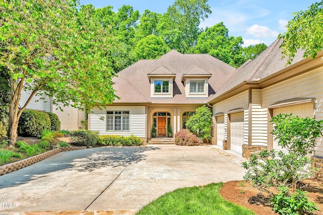 view of front facade featuring driveway, roof with shingles, and a garage