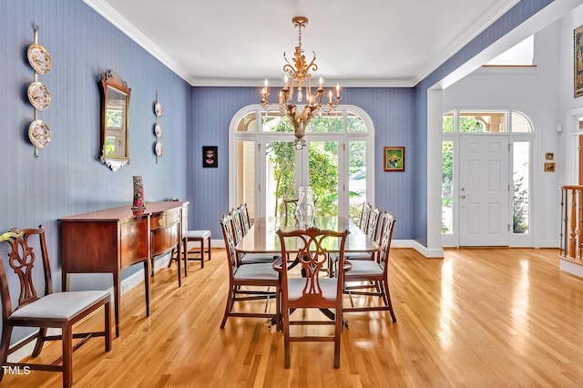 dining space featuring an inviting chandelier, ornamental molding, wallpapered walls, and light wood finished floors
