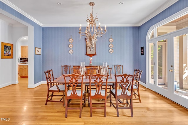 dining area featuring arched walkways, baseboards, light wood finished floors, a notable chandelier, and ornamental molding