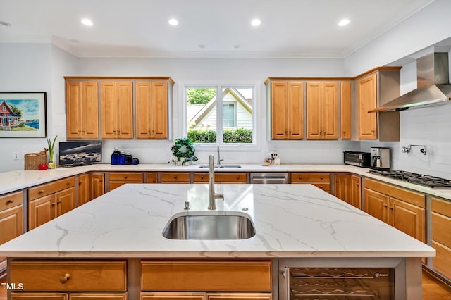 kitchen with gas cooktop, a center island with sink, a sink, and wall chimney exhaust hood