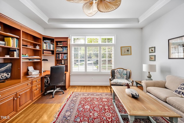 office space with light wood-type flooring, ornamental molding, a raised ceiling, and built in study area