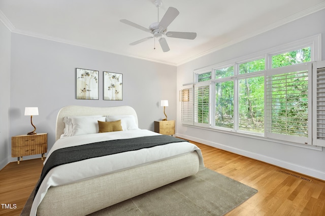 bedroom with a ceiling fan, visible vents, crown molding, wood finished floors, and baseboards