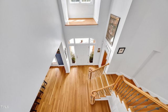 foyer with baseboards, stairs, wood finished floors, and a towering ceiling