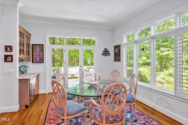 dining space with crown molding, baseboards, and light wood-style flooring