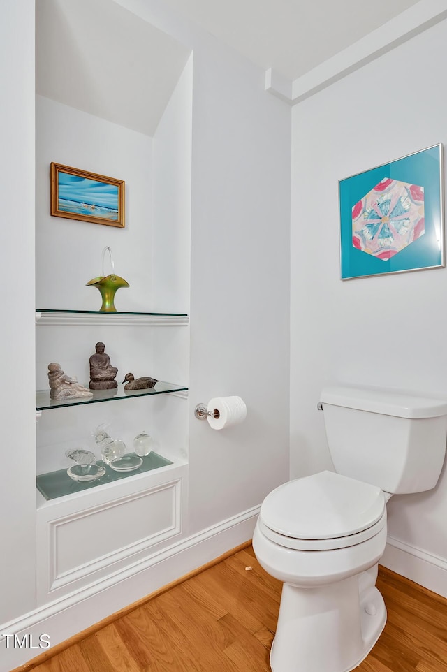bathroom featuring baseboards, wood finished floors, and toilet