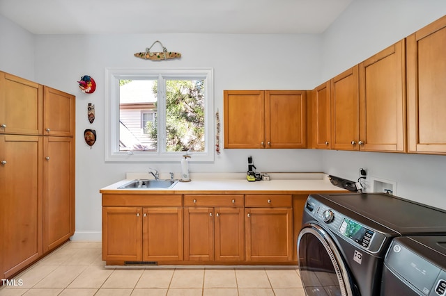 clothes washing area with a sink, light tile patterned floors, cabinet space, and washer and dryer
