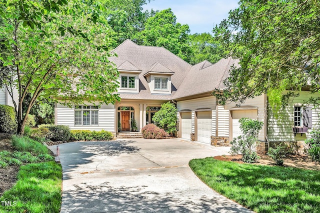 craftsman-style house with an attached garage, a shingled roof, driveway, and stone siding