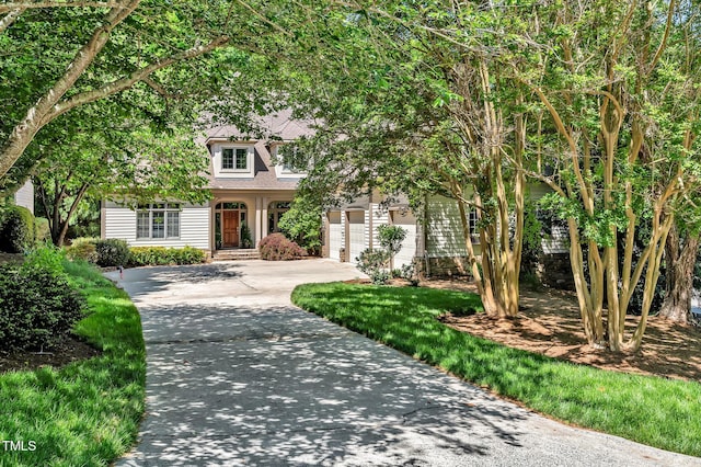 view of property hidden behind natural elements featuring an attached garage, driveway, and roof with shingles
