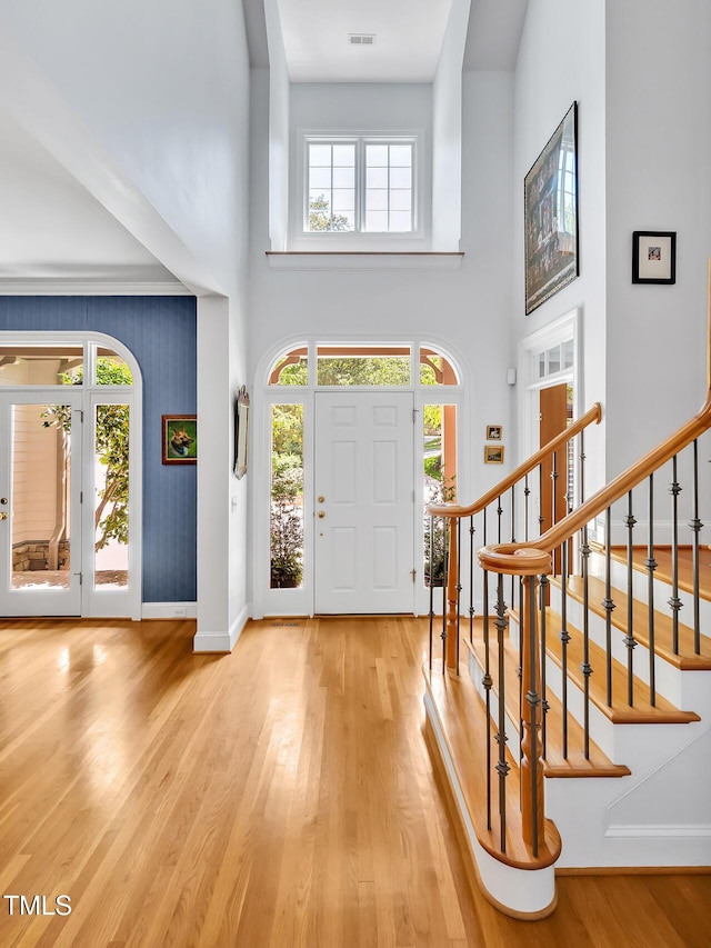 foyer featuring a towering ceiling, visible vents, wood finished floors, baseboards, and stairs
