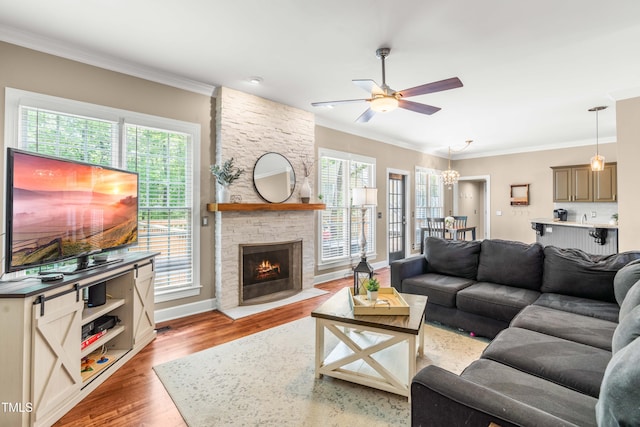 8600 Clivedon Dr, Raleigh, NC 27615 - living room featuring crown molding, ceiling fan, a stone fireplace, baseboards, and light wood-type flooring