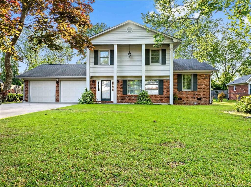 view of front facade featuring a front lawn, a garage, a shingled roof, driveway, and brick siding