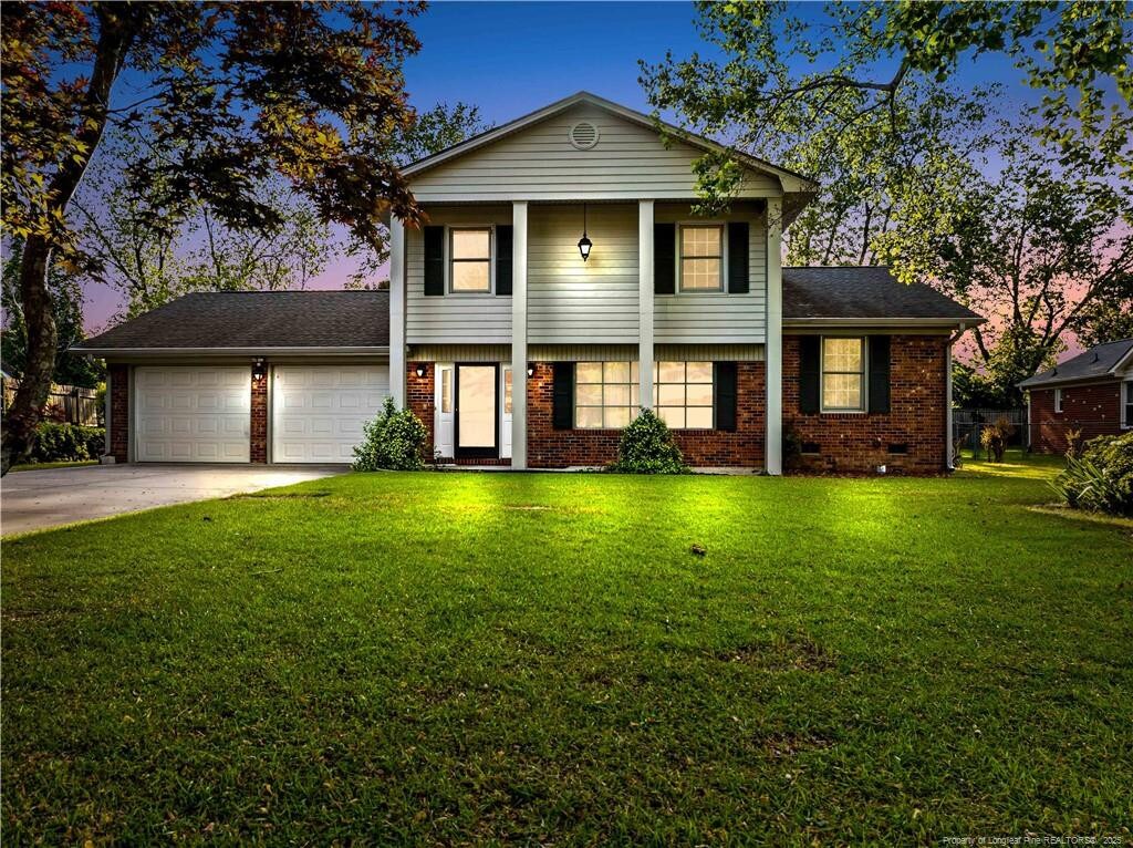 view of front of home with brick siding, a front lawn, driveway, and an attached garage