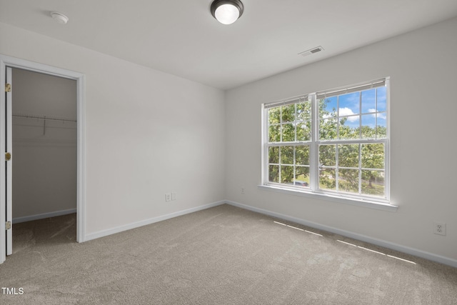 unfurnished bedroom with visible vents, baseboards, a closet, a spacious closet, and carpet flooring