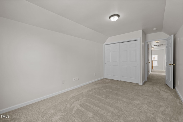 unfurnished bedroom with a closet, vaulted ceiling, and light carpet