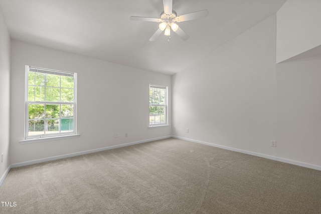 carpeted spare room with baseboards, a ceiling fan, plenty of natural light, and lofted ceiling