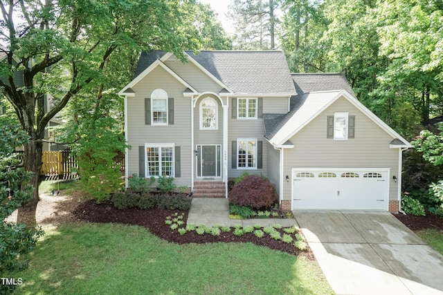 colonial home featuring concrete driveway, an attached garage, and roof with shingles