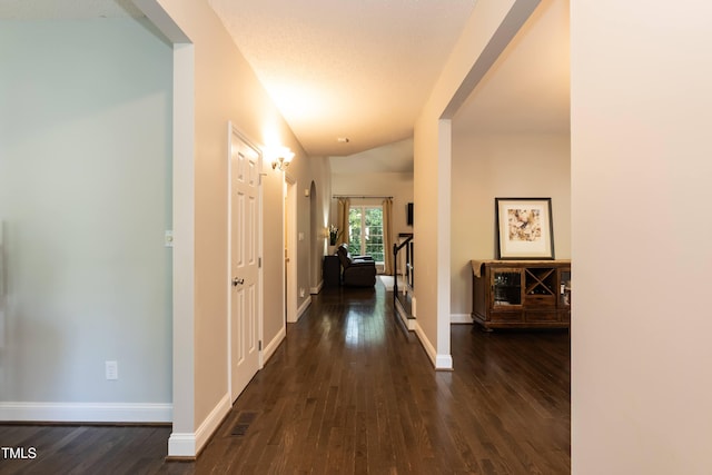 hallway featuring dark wood finished floors and baseboards