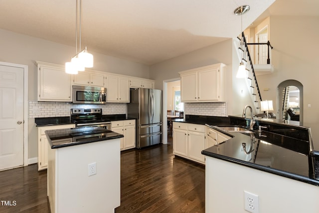 kitchen featuring stainless steel appliances, a sink, dark countertops, a peninsula, and backsplash