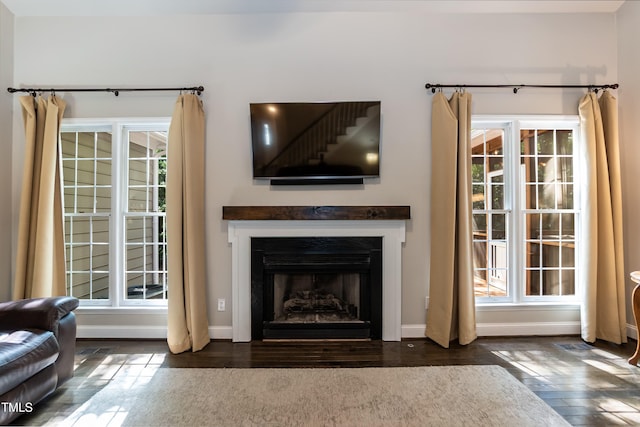 living room featuring wood-type flooring, a fireplace with flush hearth, and baseboards