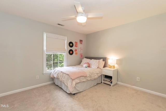 bedroom featuring light colored carpet, baseboards, and a ceiling fan