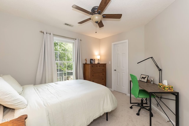 bedroom featuring light carpet, ceiling fan, and a desk