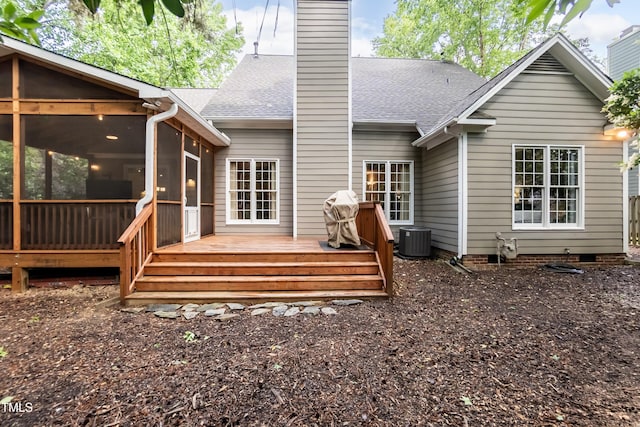 rear view of property with a chimney, a sunroom, cooling unit, a wooden deck, and a shingled roof