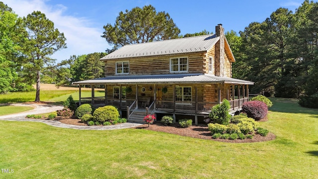 407 Howard Tant Rd, Zebulon, NC 27597 - view of front of home with log siding, a front yard, a chimney, covered porch, and metal roof