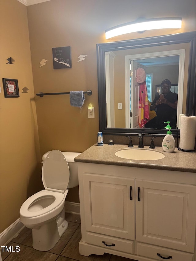 half bath with toilet, baseboards, tile patterned flooring, and vanity