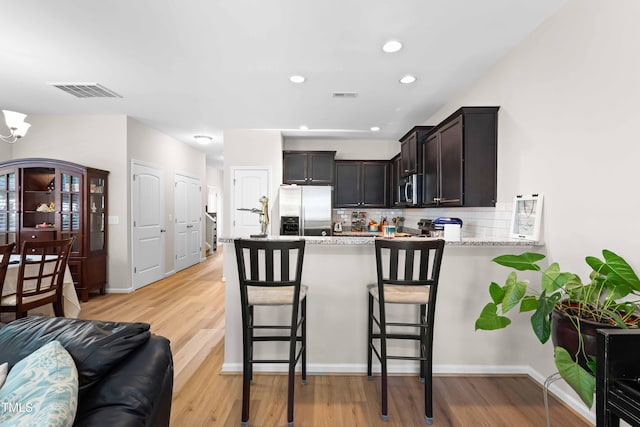 513 Commons Dr, Holly Springs, NC 27540 - kitchen featuring visible vents, a peninsula, light wood finished floors, backsplash, and stainless steel appliances