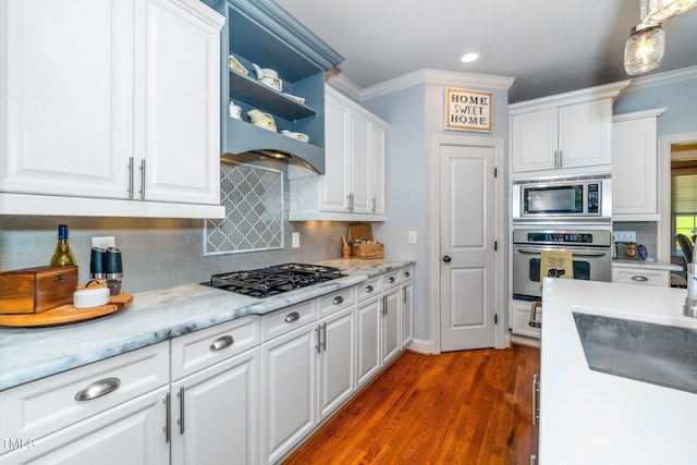 kitchen with appliances with stainless steel finishes, white cabinets, backsplash, dark wood-style floors, and ornamental molding