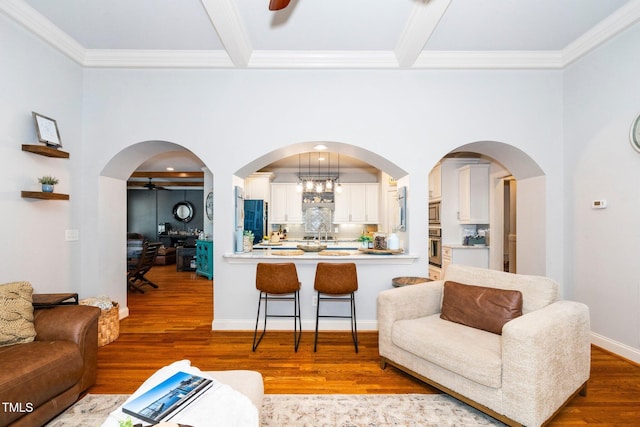 living room featuring ornamental molding, wood finished floors, ceiling fan, beamed ceiling, and baseboards