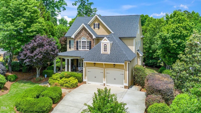 traditional-style home featuring a shingled roof, stone siding, concrete driveway, board and batten siding, and an attached garage