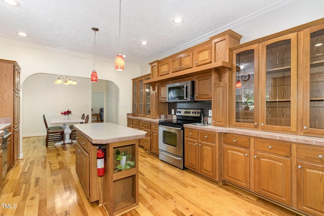 kitchen with brown cabinetry, stainless steel appliances, and arched walkways