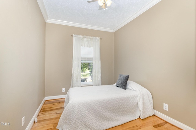 bedroom featuring baseboards, crown molding, and wood finished floors