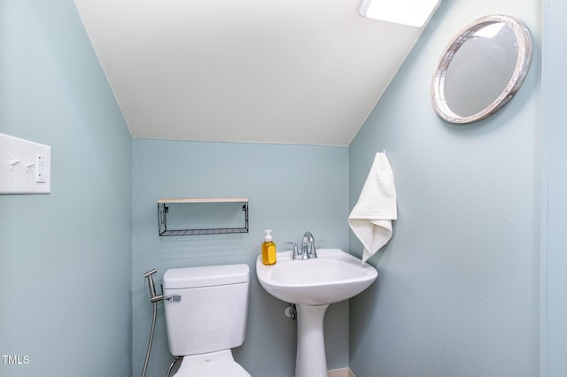 half bathroom featuring vaulted ceiling and toilet