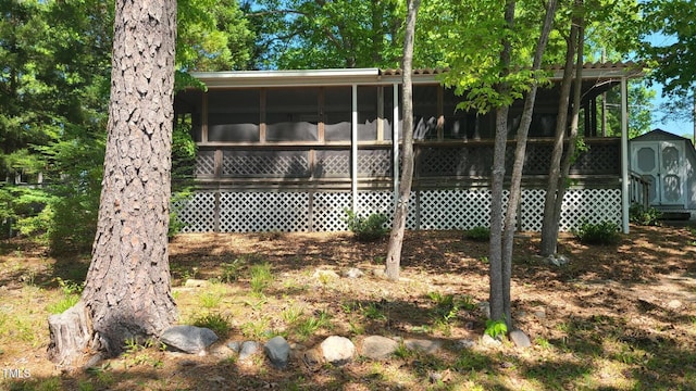 rear view of property with an outdoor structure, a shed, and a sunroom