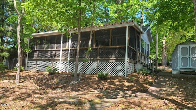 rear view of property featuring an outdoor structure, a shed, and a sunroom