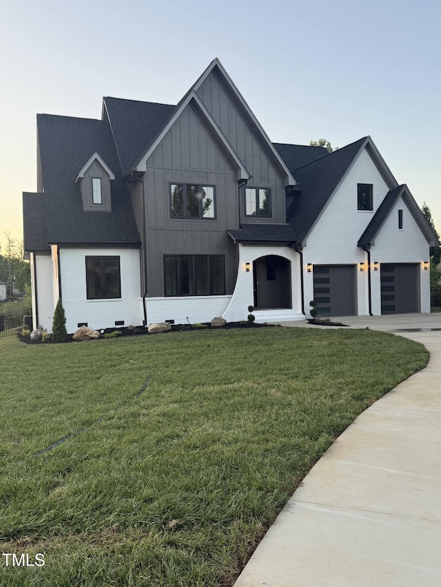 modern inspired farmhouse featuring board and batten siding, a shingled roof, a garage, driveway, and a front lawn