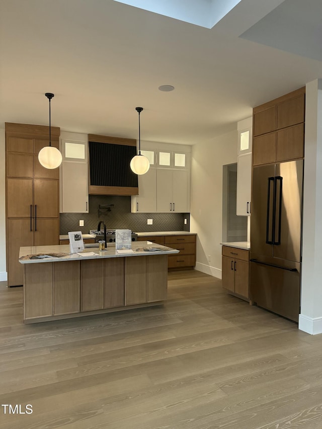 kitchen with extractor fan, light wood-type flooring, stainless steel fridge, and baseboards