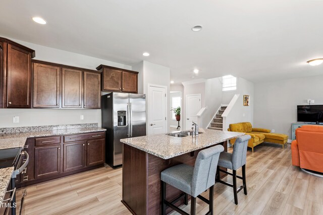 147 Antler Steel Dr, Clayton, NC 27527 - kitchen with open floor plan, a kitchen bar, a sink, light wood-style flooring, and stainless steel appliances