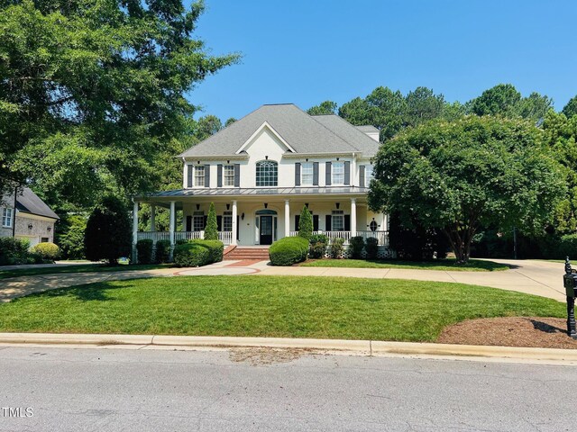 8729 Valentine Ct, Raleigh, NC 27613 - colonial home with covered porch, a standing seam roof, concrete driveway, a front yard, and metal roof