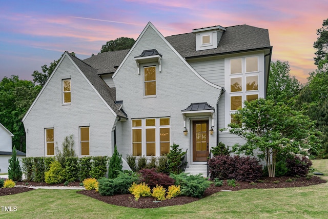 view of front of house with brick siding, a shingled roof, a front lawn, and entry steps