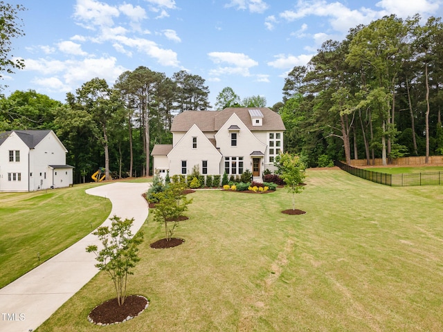 view of front of home featuring fence, concrete driveway, and a front lawn