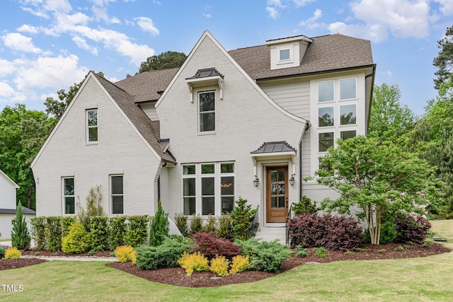 view of front facade with brick siding, a shingled roof, a front yard, and entry steps