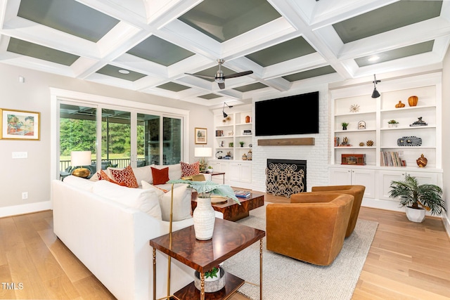 living room with ceiling fan, a brick fireplace, baseboards, light wood-type flooring, and beamed ceiling